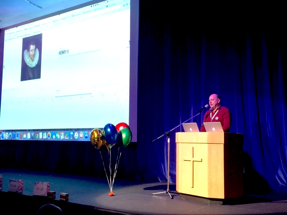 Richard Poth delivering a keynote presentation on a large auditorium stage